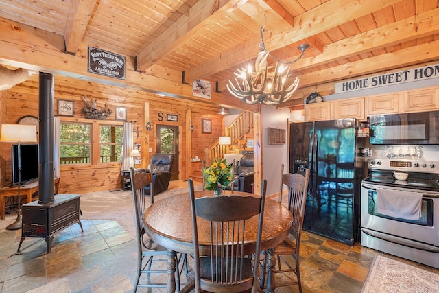 dining space featuring beamed ceiling, a wood stove, wooden walls, and wood ceiling