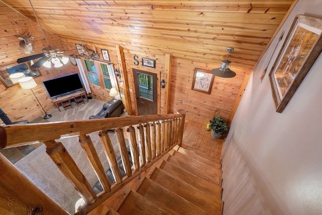 stairway with vaulted ceiling, ceiling fan, wooden walls, hardwood / wood-style flooring, and wooden ceiling