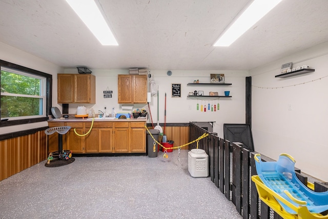 kitchen with sink, a textured ceiling, and wood walls