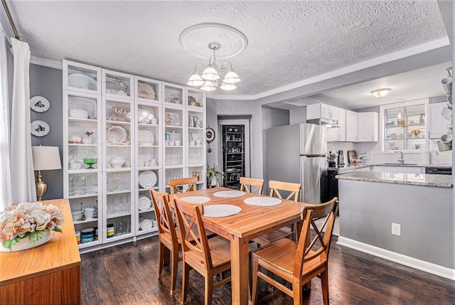 dining space with sink, dark wood-type flooring, and a textured ceiling