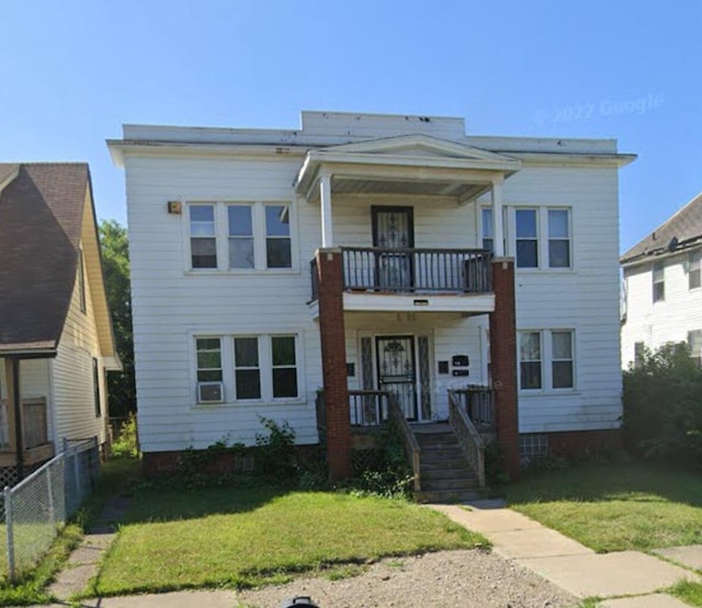 view of front of home with a porch, a balcony, and a front yard