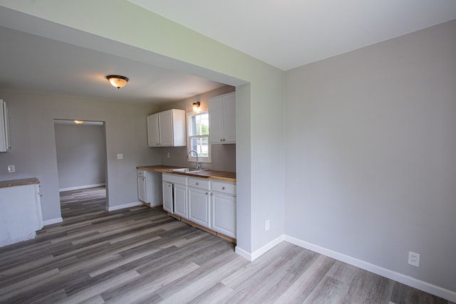 kitchen featuring butcher block countertops, sink, white cabinets, and light hardwood / wood-style flooring