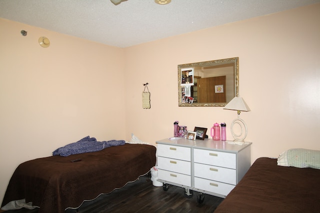 bedroom featuring a textured ceiling and dark hardwood / wood-style flooring