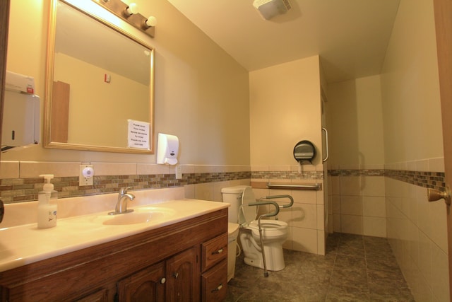 bathroom with tile patterned flooring, vanity, toilet, and tile walls