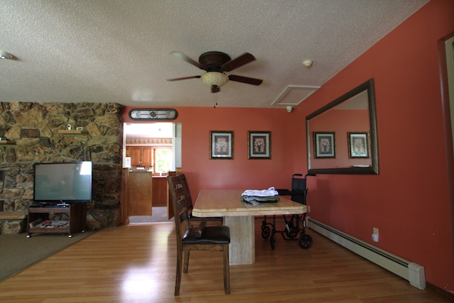 dining area with ceiling fan, hardwood / wood-style floors, a baseboard radiator, and a textured ceiling