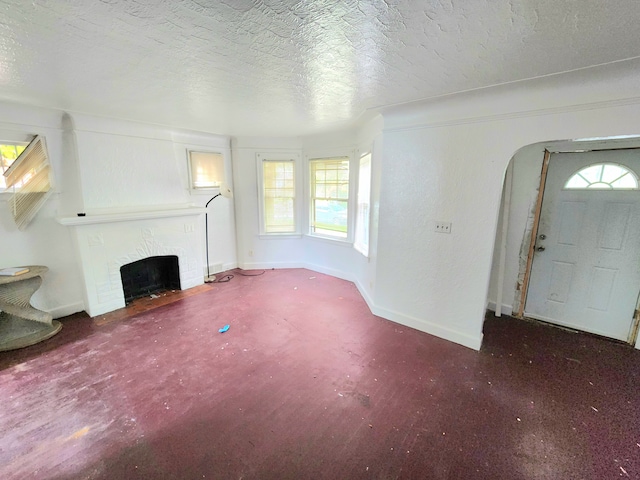 unfurnished living room featuring carpet flooring, a textured ceiling, and a brick fireplace