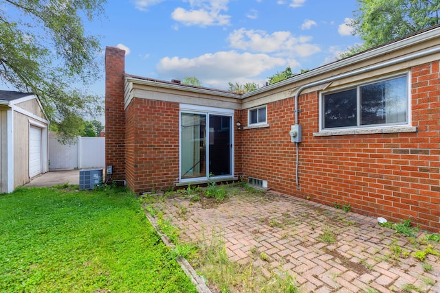 back of property with a yard, an outdoor structure, cooling unit, a garage, and a patio area