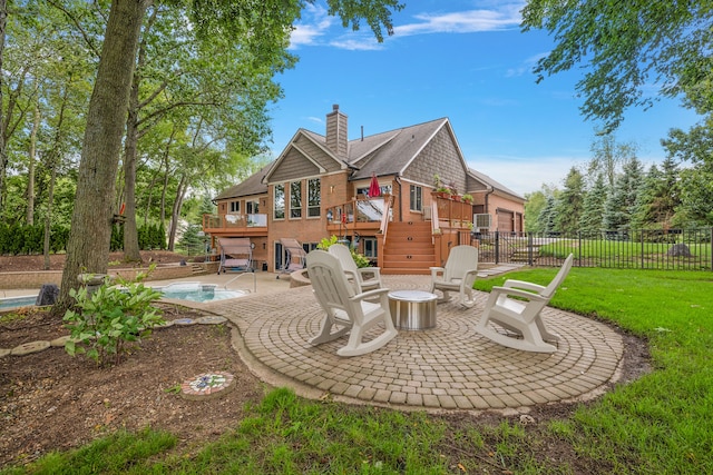 rear view of property with a lawn, a swimming pool side deck, a patio, and an outdoor fire pit