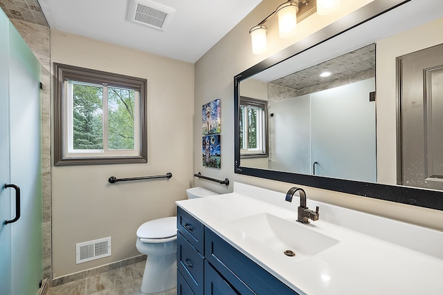 bathroom with a shower with door, vanity, and toilet