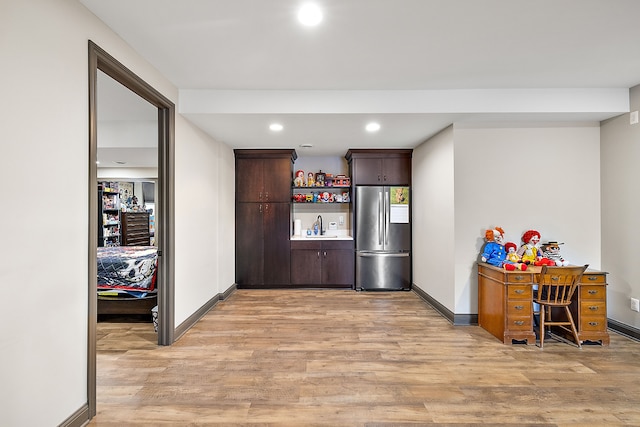 kitchen with dark brown cabinets, stainless steel fridge, sink, and light hardwood / wood-style flooring