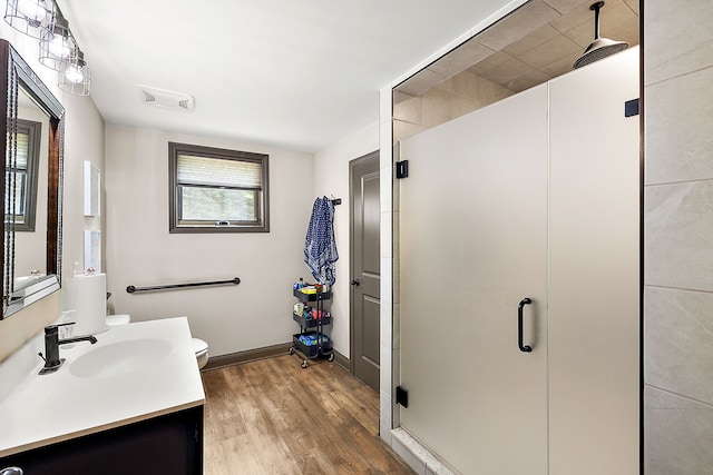 bathroom featuring vanity, wood-type flooring, an enclosed shower, and toilet