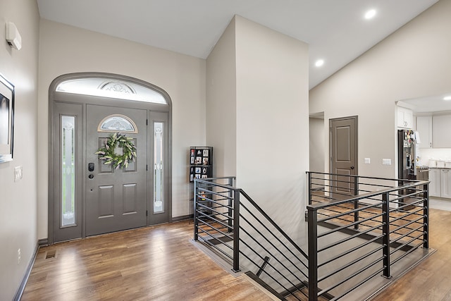 foyer entrance with high vaulted ceiling and wood-type flooring