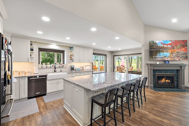 kitchen featuring sink, a kitchen island, stainless steel dishwasher, dark hardwood / wood-style floors, and white cabinets