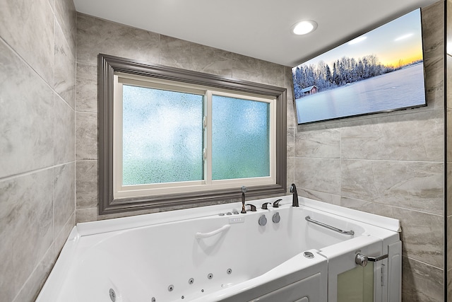 bathroom featuring a tub, tile walls, and a healthy amount of sunlight