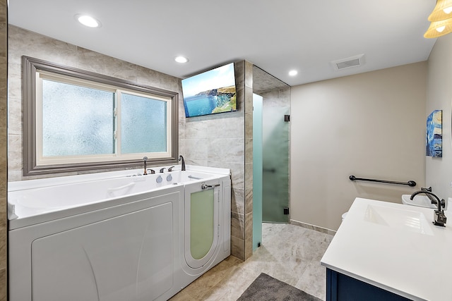 bathroom featuring separate shower and tub, vanity, and tile walls