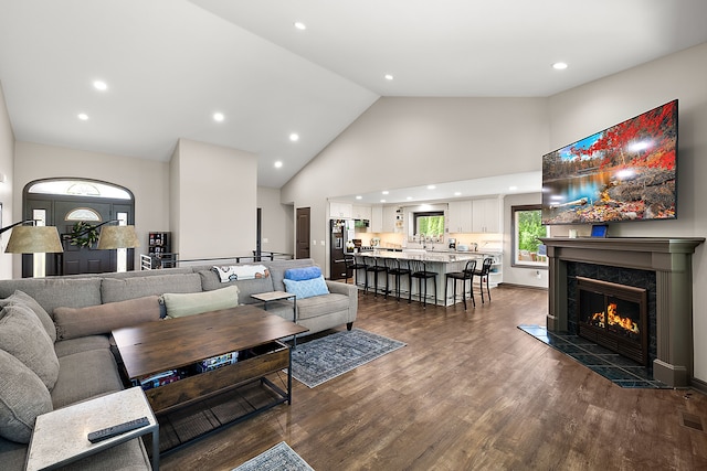 living room with a tile fireplace, dark hardwood / wood-style floors, and high vaulted ceiling