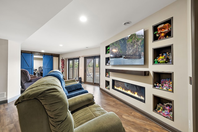 12120 Shaffer Rd, Davisburg, MI 48350 - living area with a barn door, a glass covered fireplace, wood finished floors, recessed lighting, and baseboards