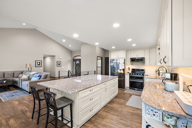 kitchen featuring dark hardwood / wood-style flooring, stainless steel appliances, white cabinetry, a kitchen island, and lofted ceiling