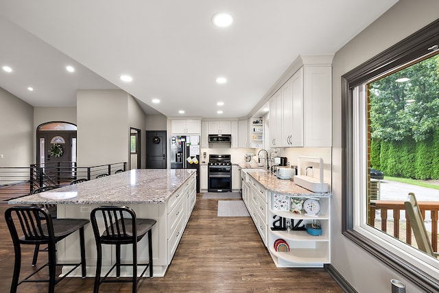 kitchen with a healthy amount of sunlight, white cabinets, range with gas stovetop, and dark hardwood / wood-style floors