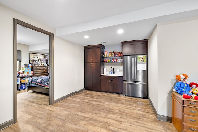 kitchen with stainless steel fridge, sink, dark brown cabinets, and light wood-type flooring