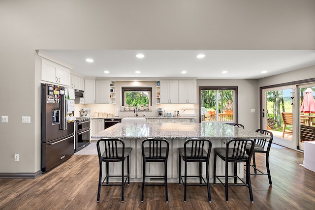 kitchen featuring white cabinetry, a center island, stainless steel appliances, and dark hardwood / wood-style floors