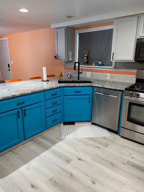 kitchen with appliances with stainless steel finishes, tasteful backsplash, blue cabinets, sink, and light hardwood / wood-style floors