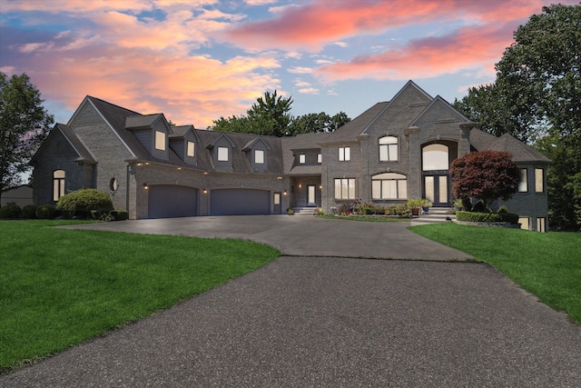 french country home featuring a garage and a lawn