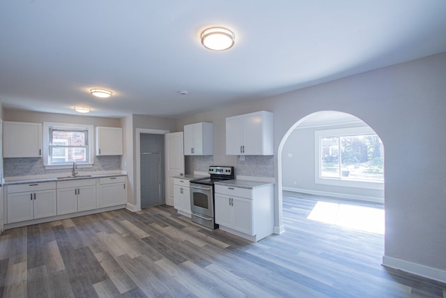 kitchen featuring white cabinets, hardwood / wood-style flooring, stainless steel range with electric cooktop, and sink