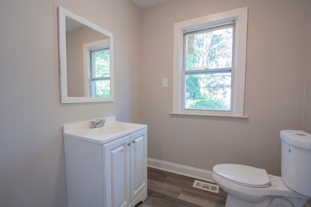 bathroom with hardwood / wood-style flooring, vanity, a healthy amount of sunlight, and toilet