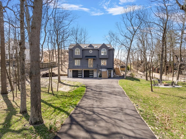 view of front facade featuring aphalt driveway, an attached garage, and a front yard