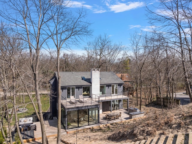 rear view of house with roof with shingles, a chimney, stairway, a patio area, and a deck