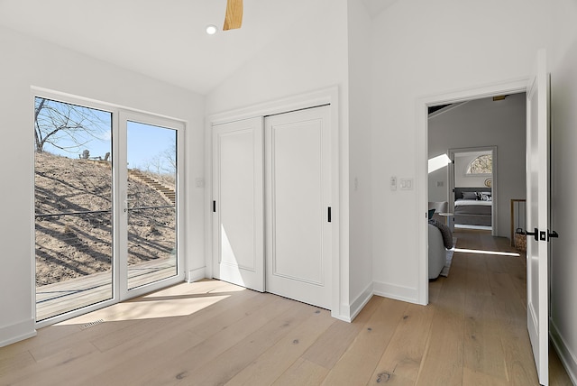 interior space featuring access to outside, light wood-style floors, vaulted ceiling, recessed lighting, and baseboards