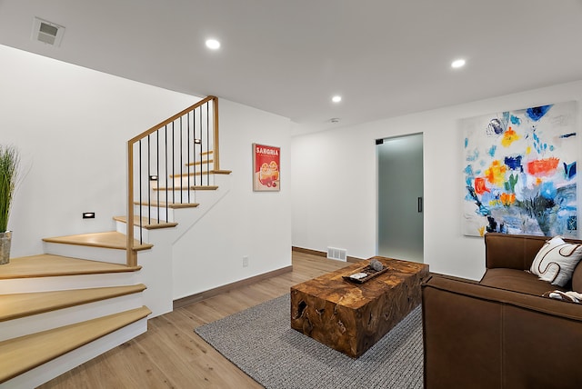 living area featuring visible vents, light wood-type flooring, recessed lighting, and stairs