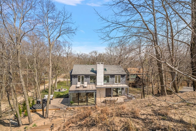 rear view of property with a patio area, a shingled roof, a deck, and a chimney