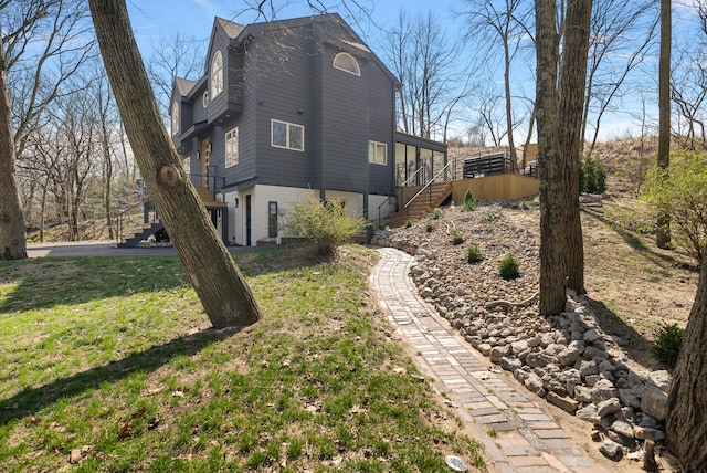 view of home's exterior with a yard and stairway