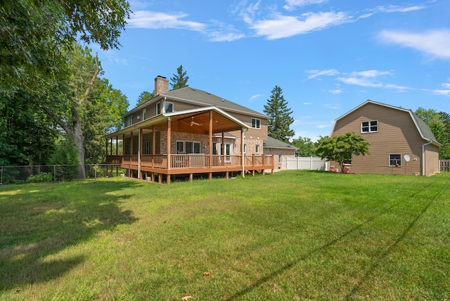 back of property with ceiling fan, a wooden deck, and a lawn