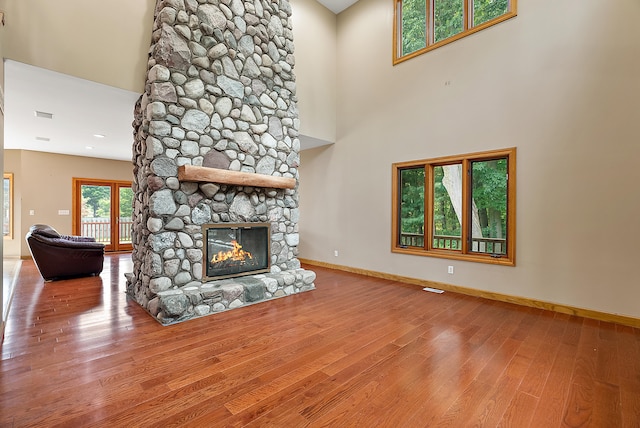 unfurnished living room featuring a fireplace, a high ceiling, and hardwood / wood-style flooring