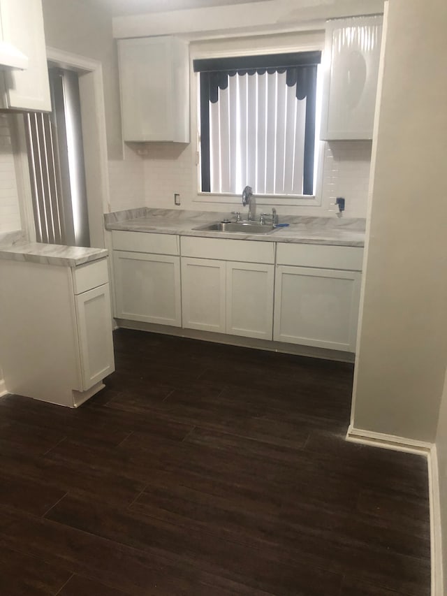 kitchen featuring light stone countertops, sink, dark wood-type flooring, tasteful backsplash, and white cabinets