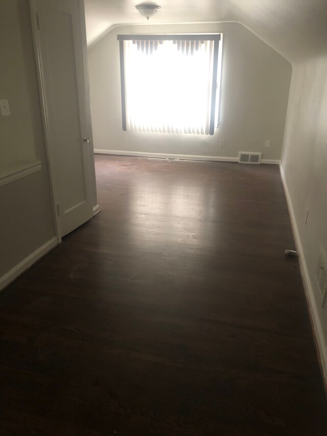 additional living space with dark hardwood / wood-style floors and vaulted ceiling