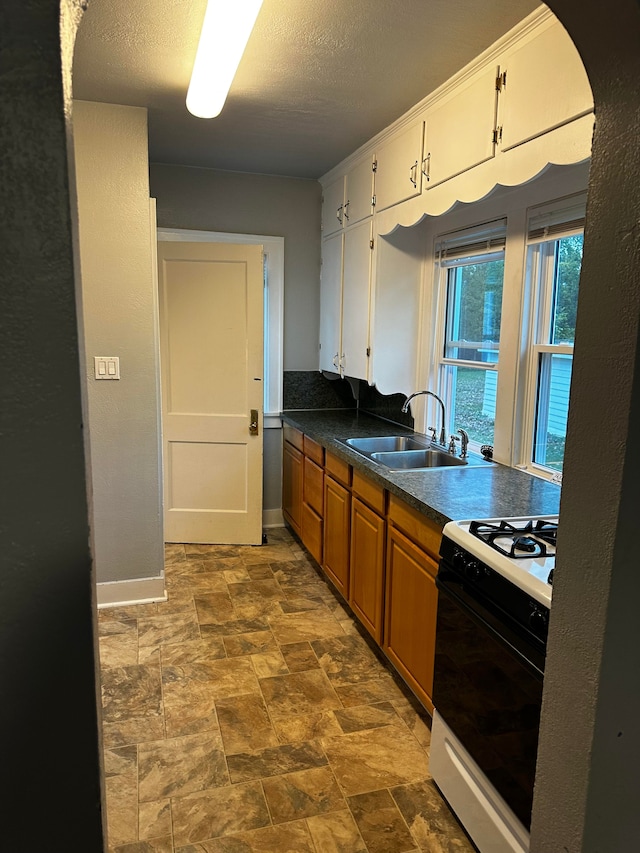 kitchen featuring white cabinets, a textured ceiling, white gas range oven, and sink