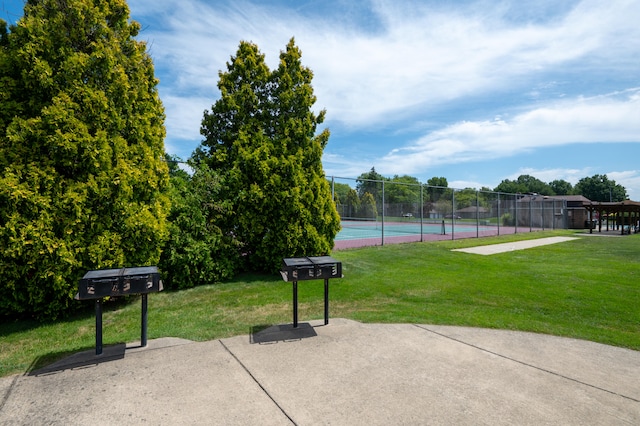 view of property's community with a yard and tennis court