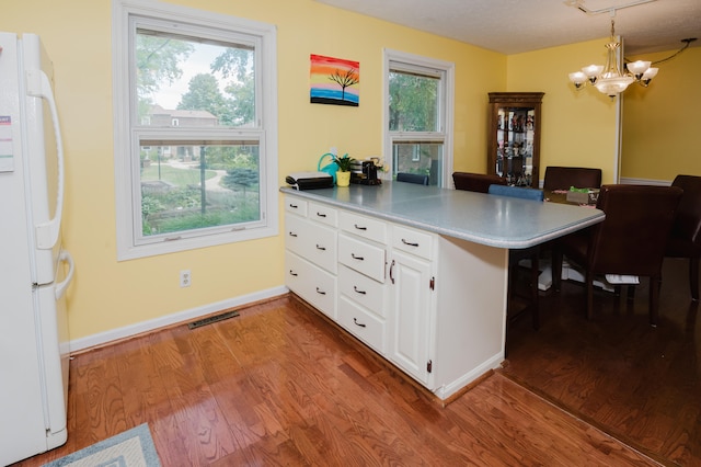 kitchen featuring kitchen peninsula, white refrigerator, light hardwood / wood-style flooring, and a breakfast bar