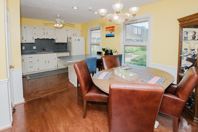 dining space featuring sink, hardwood / wood-style floors, and ceiling fan with notable chandelier