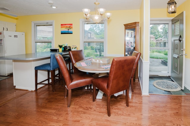 dining space featuring wood-type flooring, a wealth of natural light, and an inviting chandelier