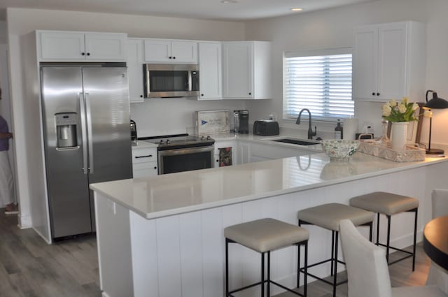 kitchen featuring kitchen peninsula, sink, white cabinets, and appliances with stainless steel finishes