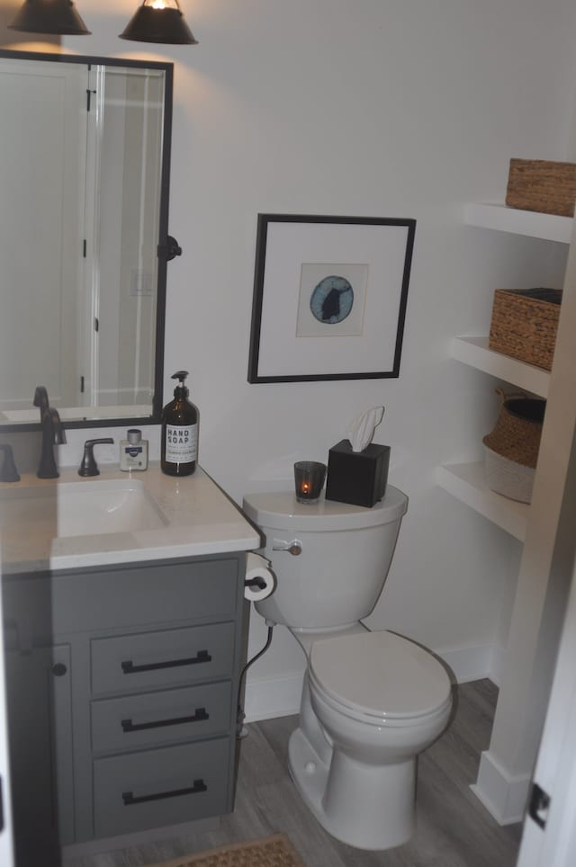 bathroom with hardwood / wood-style floors, vanity, and toilet