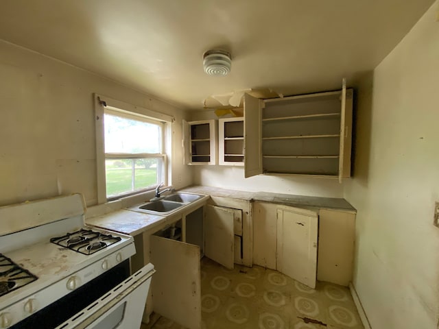 kitchen with white gas range, sink, and white cabinets