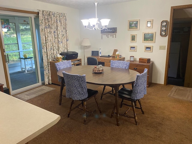 dining space with a chandelier, a textured ceiling, and dark colored carpet