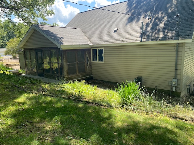 rear view of property featuring a lawn and a sunroom