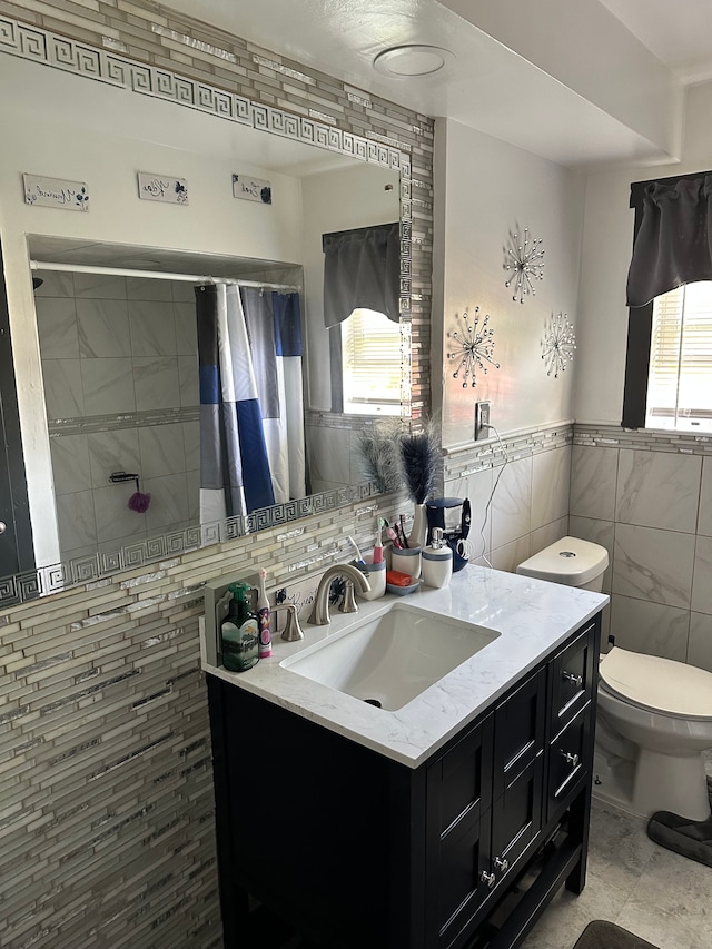 bathroom featuring vanity, a wealth of natural light, and tile walls